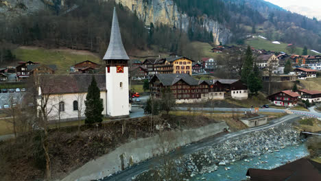Rocky-riverbanks-of-Lauterbrunnen,-Switzerland-weaves-below-cute-homes-and-subdued-facades