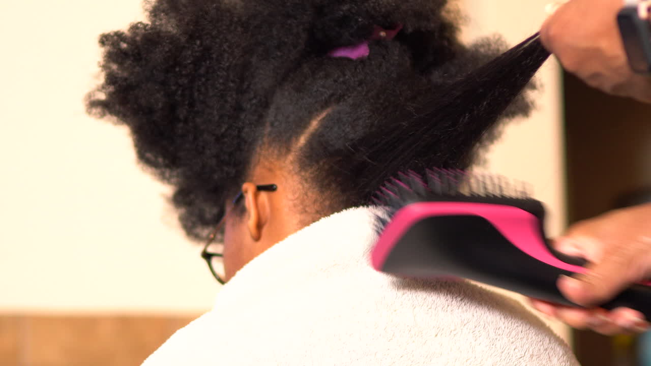 African American mother lovingly styling her daughters long hair - isolated