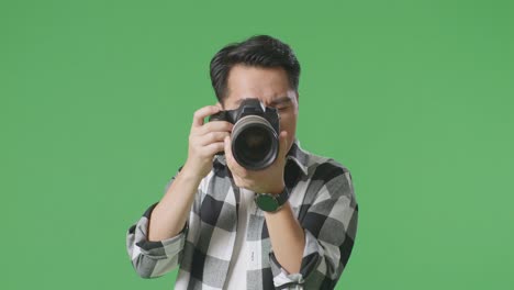 man adjusting camera on green screen