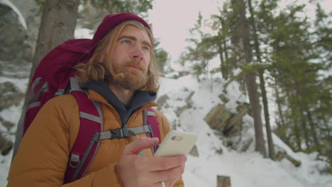 man using smartphone during winter hike