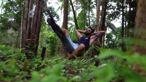 a side view of a young caucasian man swinging in a hammock in a pleasant laziness of a weekend morning