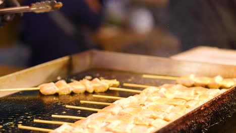 salmon skewers being grilled at a food market