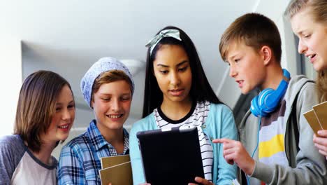 Group-of-school-friends-using-digital-tablet-in-corridor