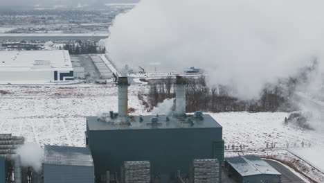 Instalación-Industrial-Que-Emite-Vapor-Contra-Un-Paisaje-Nevado,-Temporada-De-Invierno,-Vista-Aérea