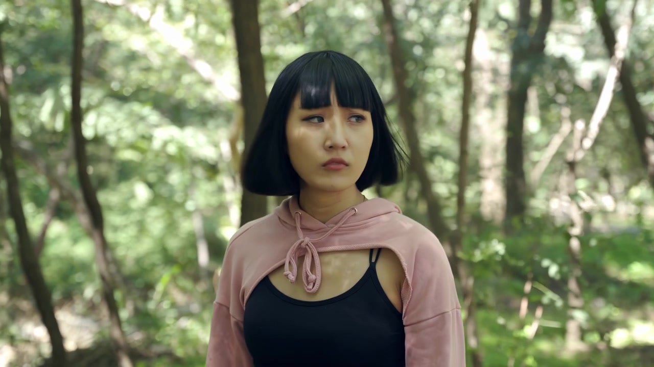 Una viaggiatrice solitaria con zaino in spalla non sa che strada prendere attraverso una foresta verde e ombrosa. La donna si guarda intorno smarrita nel bosco, l'escursionista perplessa è preoccupata per il crepuscolo imminente, temendo di aver perso il sentiero.