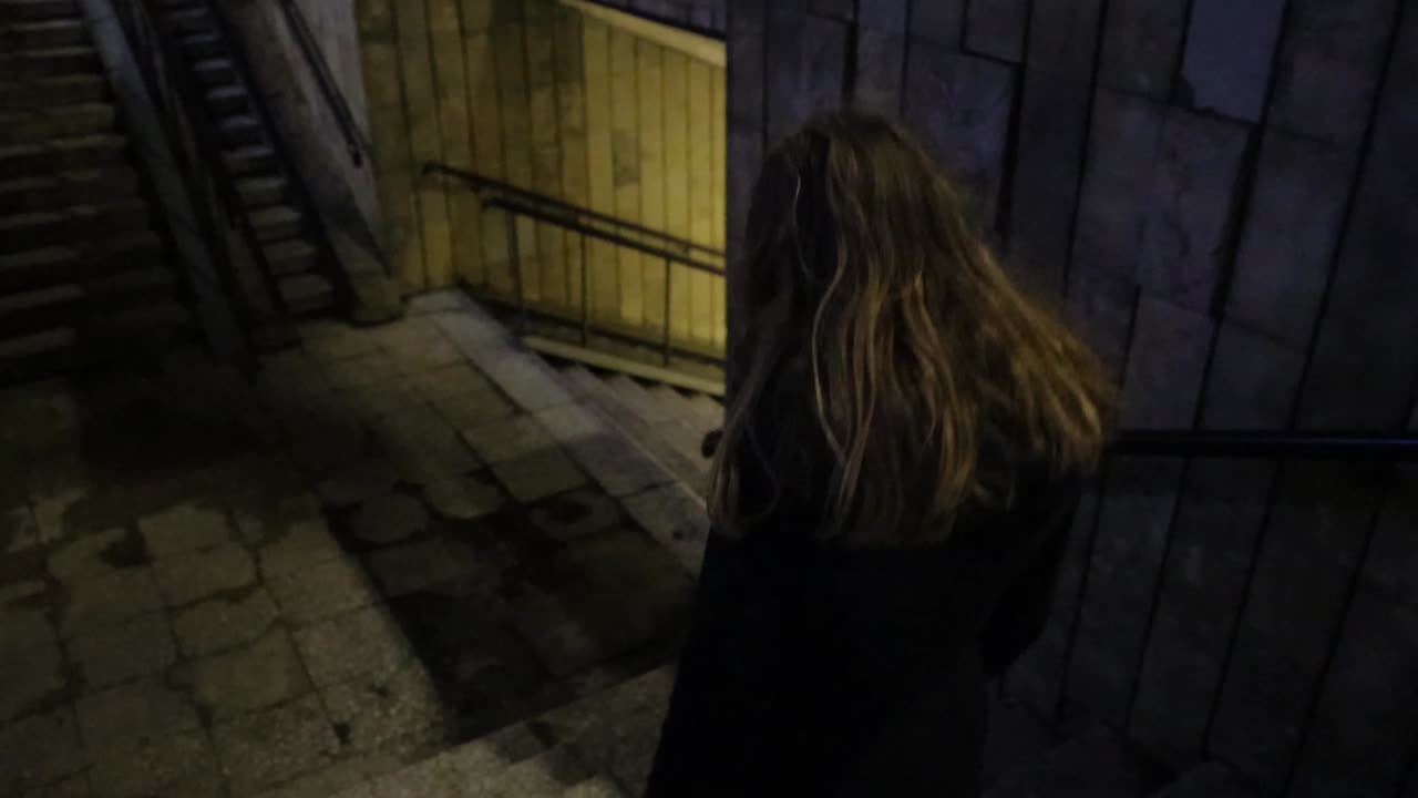 Girl walking down to the underground passage at night time