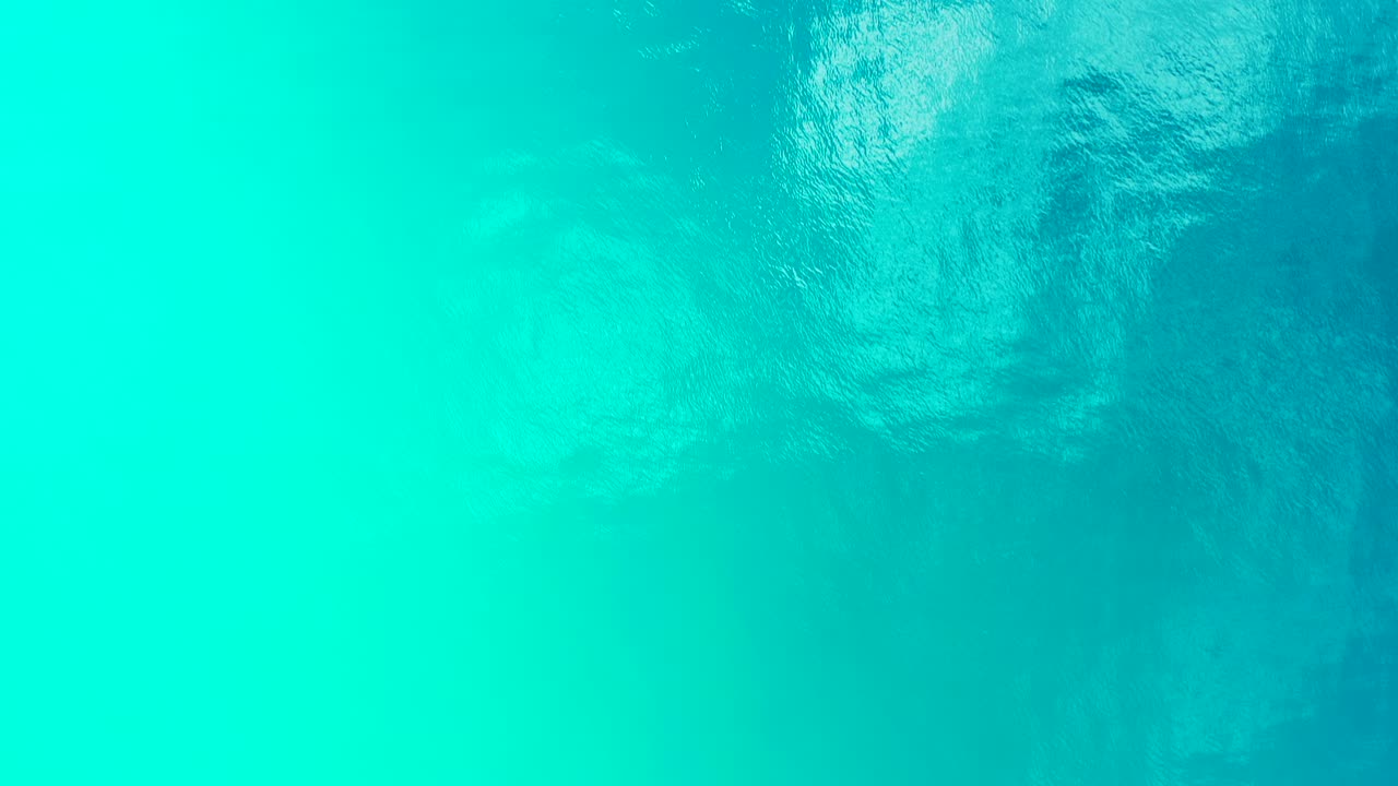 Turquoise sea texture with calm clear water reflecting sunlight near shoreline of tropical island in Myanmar, copy-space