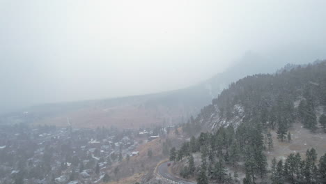 Imágenes-Aéreas-De-Drones-Sobre-La-Carretera-De-La-Ladera-De-Un-Pino-Cubierto-De-Nieve-Cerca-De-La-Montaña-Flatirons-En-Boulder,-Colorado,-EE.UU.-Durante-Una-Tormenta-De-Nieve-Nevada