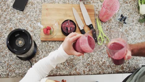 overhead of caucasian couple drinking healthy smoothies in kitchen, slow motion