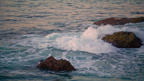 foamy waves rolling on dark rocks closeup. swirling aqua amazing ocean landscape