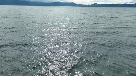 la luz del sol brillando en las aguas onduladas del lago toba, vista de la lancha rápida