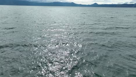 sunlight glistening on lake toba's rippling waters, speedboat view