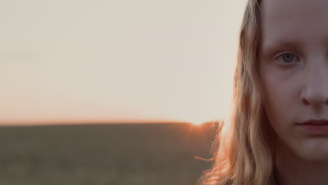 Portrait-of-a-teenage-girl-on-the-background-of-a-field-of-wheat-where-the-sun-sets