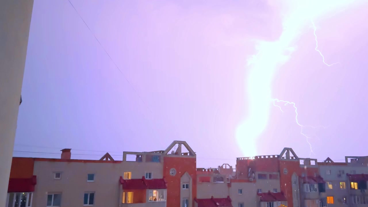 Céu Escuro e Tempestuoso com Relâmpagos sobre Edifícios Residenciais à Noite. Silhueta de Prédio de Apartamentos com Janelas Iluminadas sob Nuvens Noturnas Sombrias