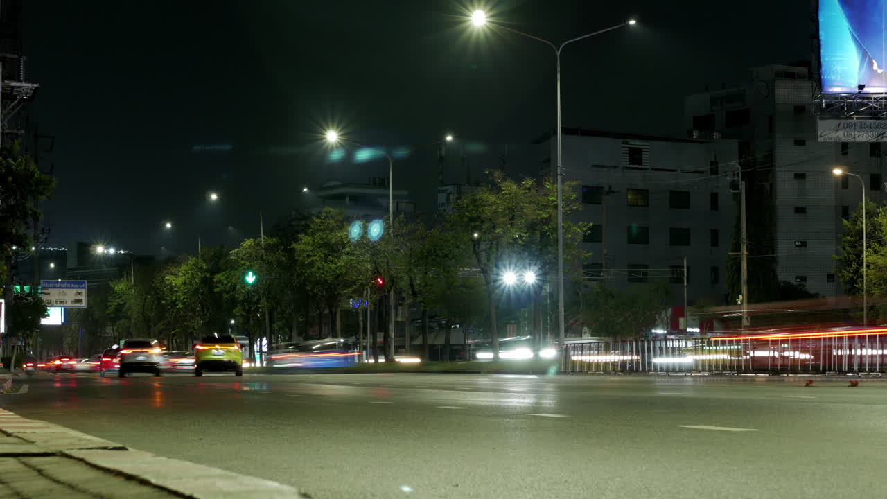 Night Timelapse shot of busy traffic of cars, taxis, buses, trucks, and other motorists at an intersection in Bangkok, Thailand