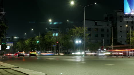 night timelapse shot of busy traffic of cars, taxis, buses, trucks, and other motorists at an intersection in bangkok, thailand