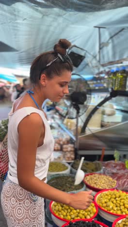 woman shopping for olives at a market