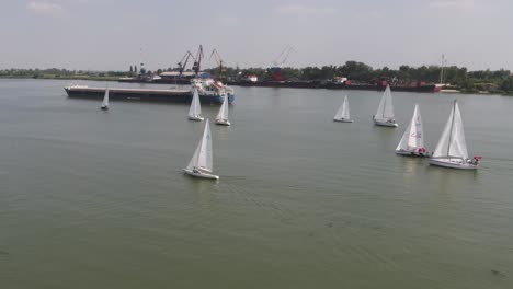 competición de vela en un río con buques de carga