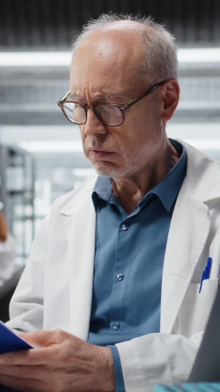 Video verticale: professionista di laboratorio senior conduce una ricerca e prende appunti