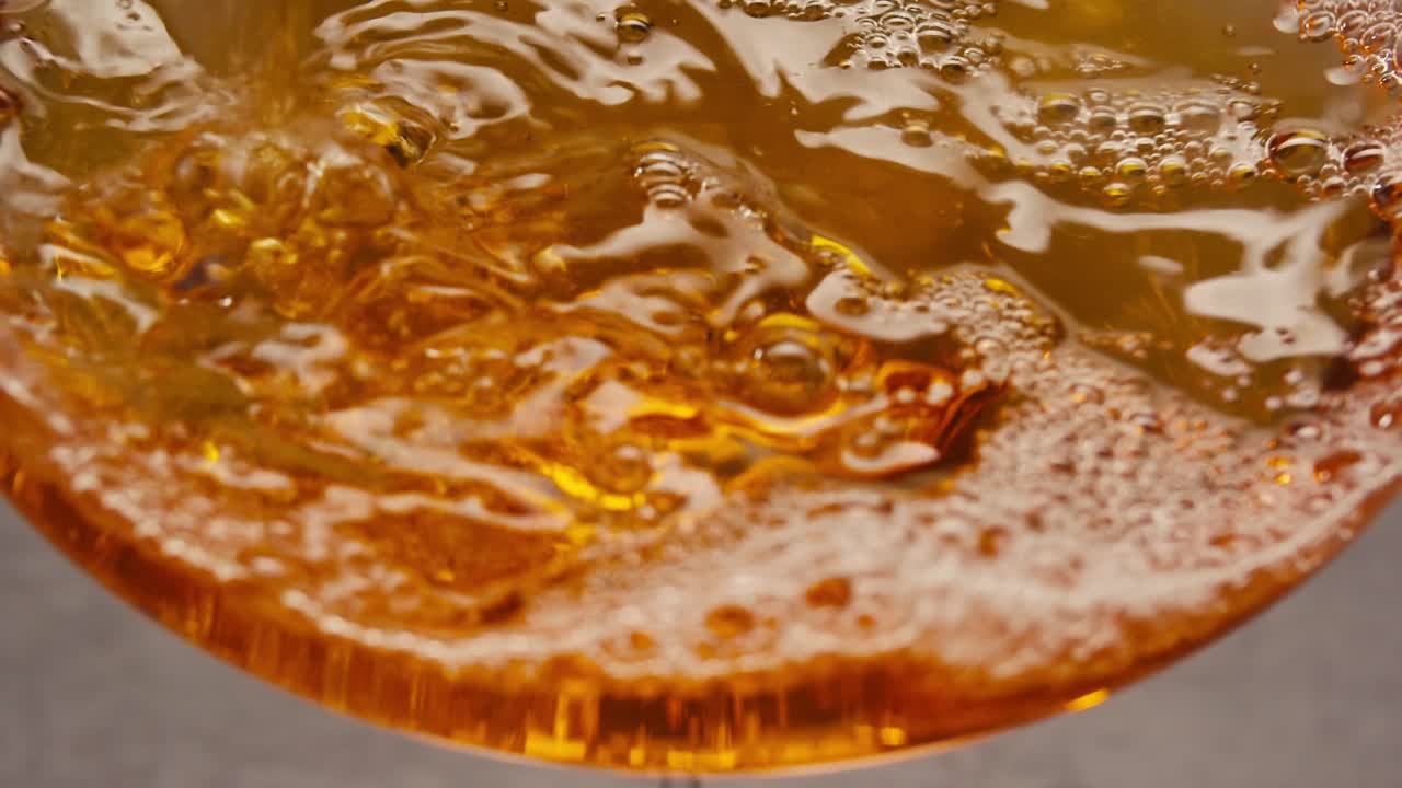 Orange or white wine bottle and glass against a sunset in a peaceful vineyard, pouring of ecological natural wine.