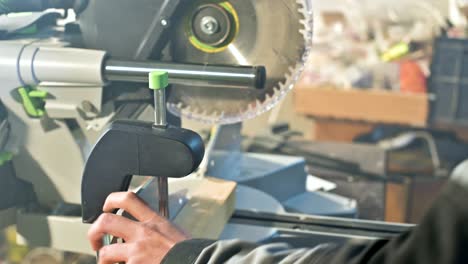 a young carpenter installs a wooden work piece in a circular sawing machine.