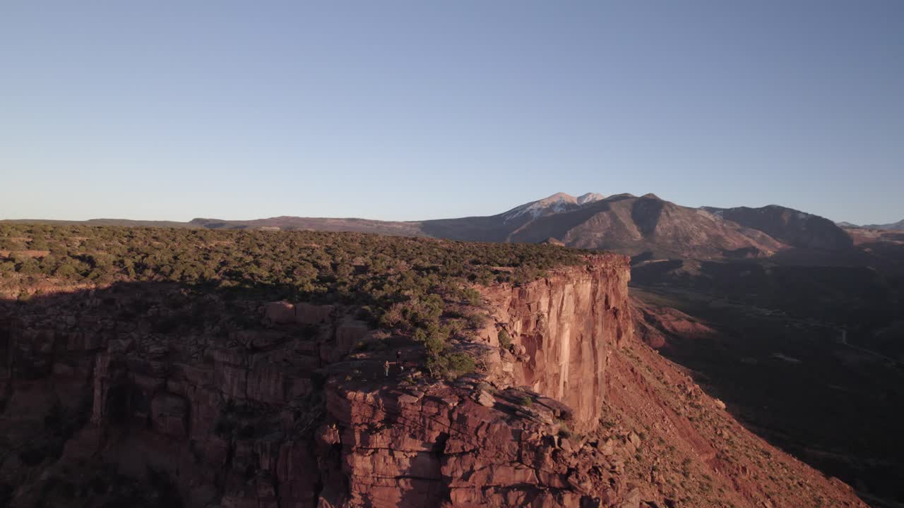 Aerial retreats from La Sal's Adobe Mesa cliffs at evening golden hour