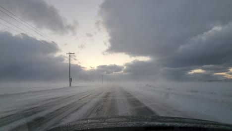 pov conduciendo a través de owen sound a lo largo de una carretera vacía con nieve ventosa cruzando la carretera