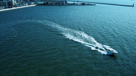 aerial tracking shot of motorboat pulling inflatable boat on baltic sea in poland