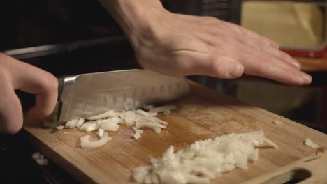 los chefs pican a mano cebollas blancas en una tabla de cortar de madera