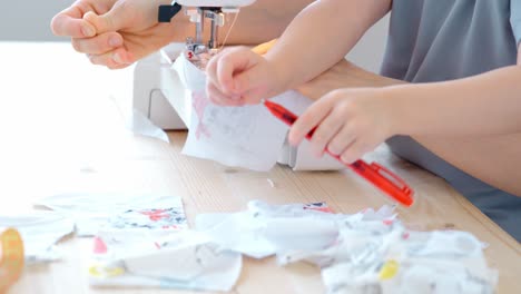 child learning to sew with mother
