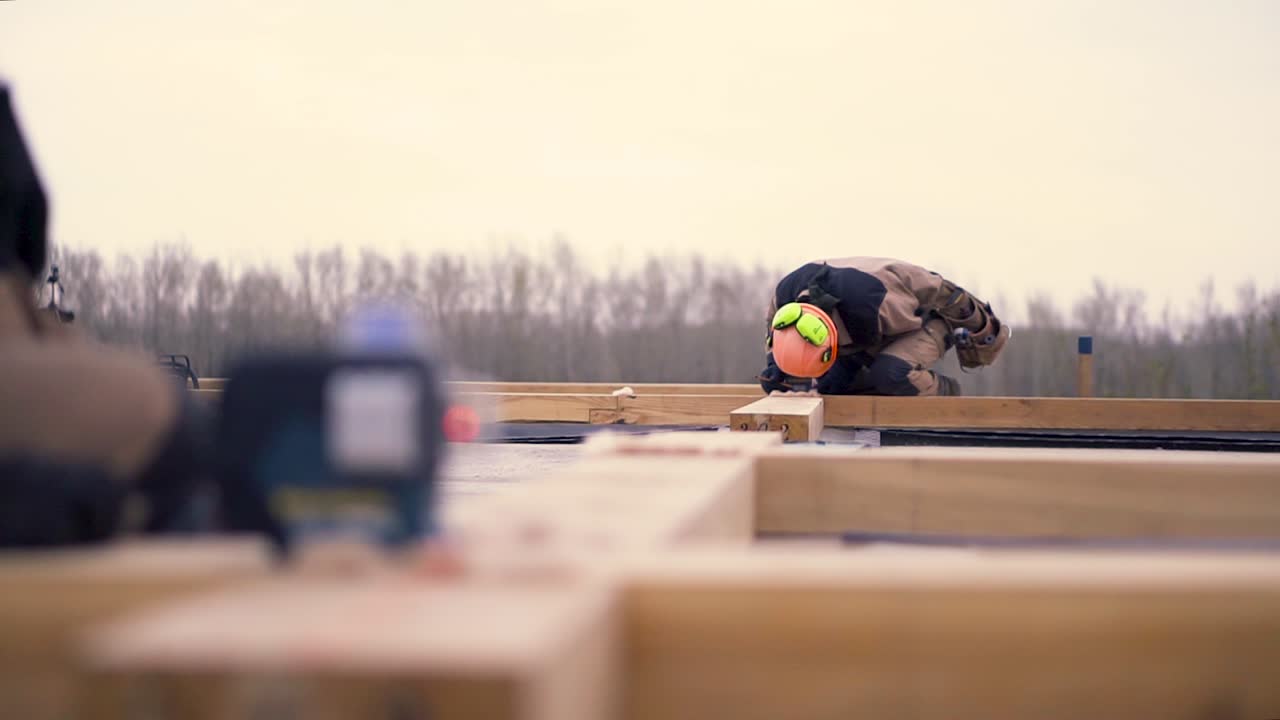 Construction Workers Using Laser Level on Wooden Beams
