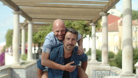 happy homosexual man carrying boyfriend on his back