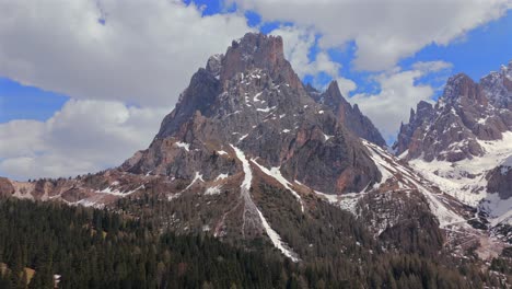 spectacular view of the langkofel mountain in the alps, featuring a snow-capped peak and dense pine forest under a bright blue sky