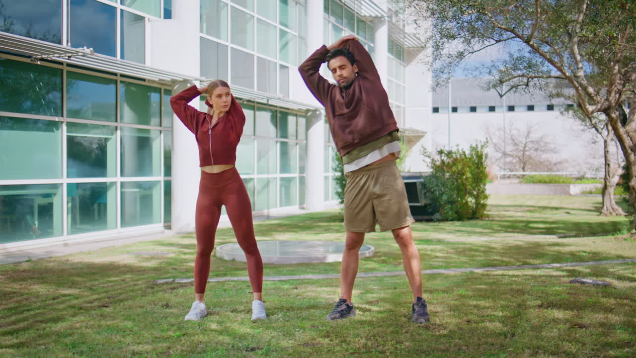 Couple doing warming exercise in city park. Two athletes training in morning