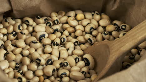 macro closeup: dry beans, healthy black-eyed peas revolve in paper bag