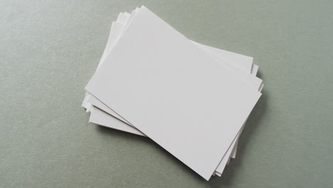 varias tarjetas de visita blancas en blanco sobre fondo verde, espacio de copia, cámara lenta