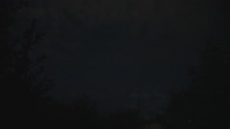 nighttime thunder flashes in dark eerie landscape during summer storm