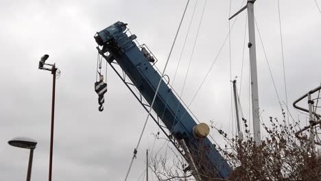 tall boat crane machinery equipment in industrial maritime dockyard alongside boats