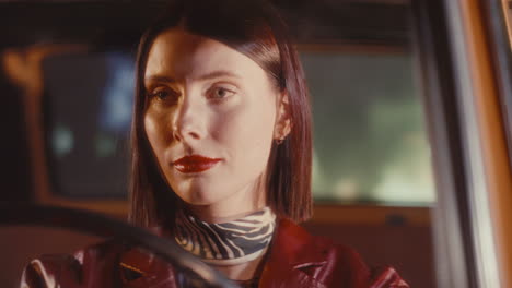 feminine woman driving classic retro car on city street at night
