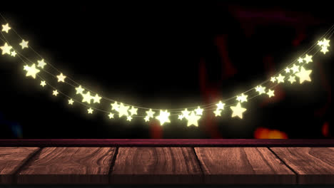 Glowing-yellow-star-shaped-fairy-light-decoration-hanging-over-wooden-plank