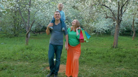 Familia-Feliz-Con-Un-Niño-Caminando-En-El-Parque-Florido