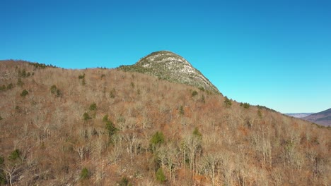 aerial footage flying up the side of a forested mountain after a late fall snow