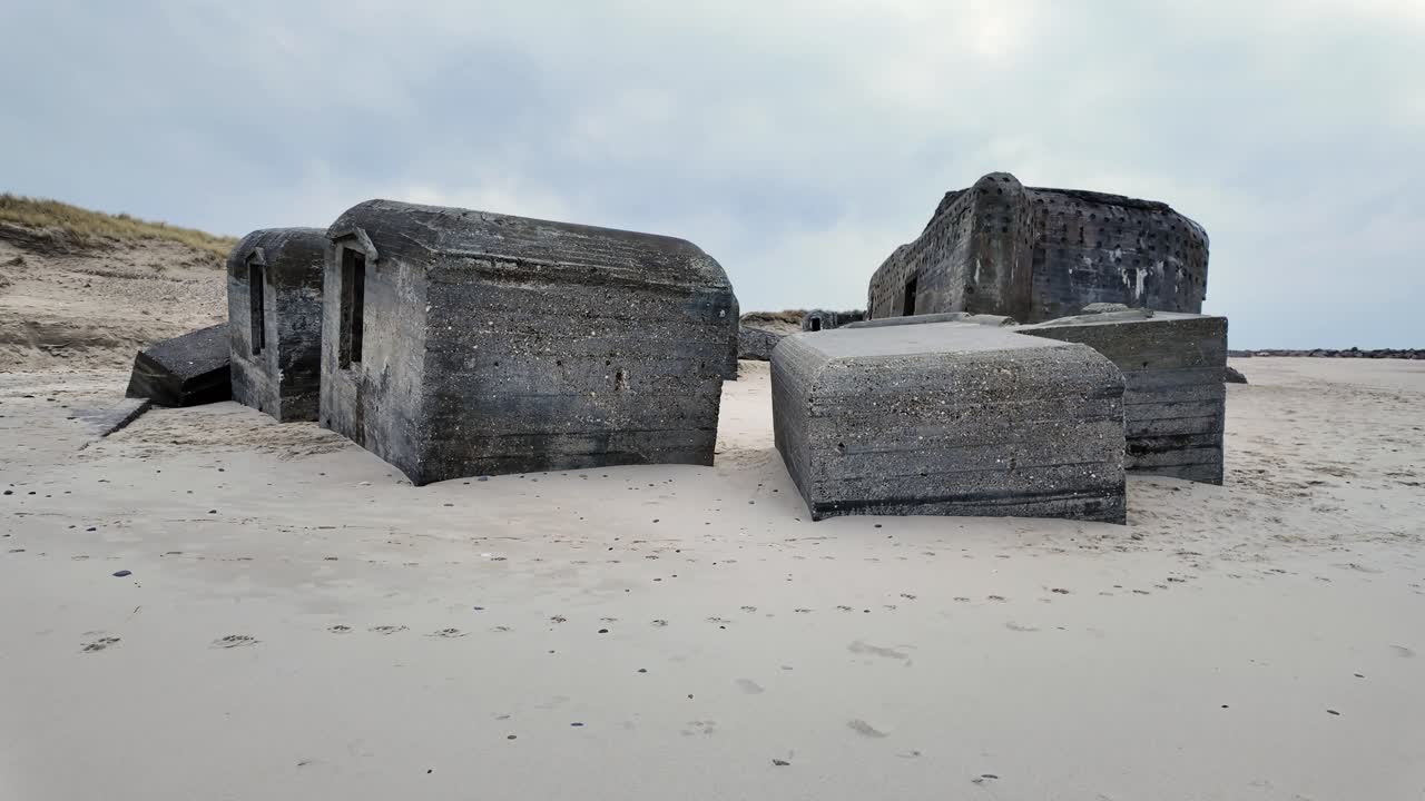 Parts of a WWII bunker lie scattered on the beach, weathered by time and the sea. Scandinavia Denmark.