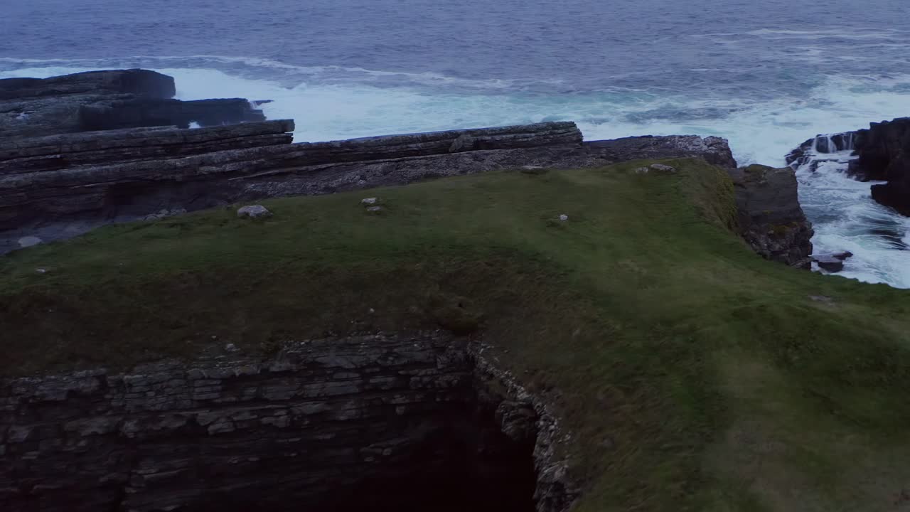 Aerial parallax of Bridges of Ross at twilight featuring rough Loop Head coast