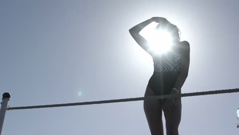 woman in swimsuit posing by a rope