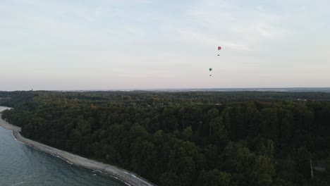 aerial view of men paragliding high in the sky, flying over the sea and coast