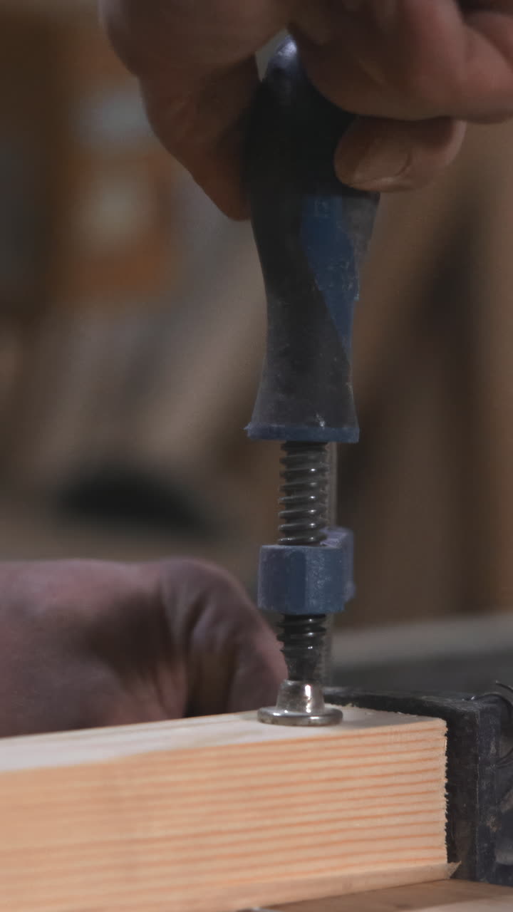 CloseUp Caucasian Carpenter Hand Fastening Screw Over Clamped Pine Board Using Screwdriver Steady Motion Warm. Media
