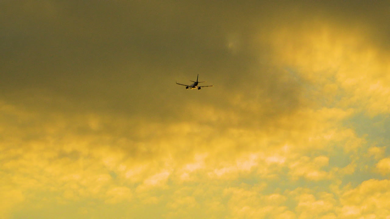 Jumbo jet below the clouds with the sun