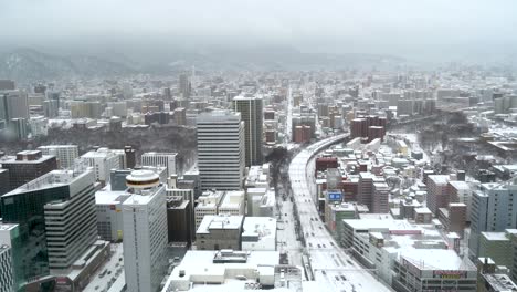 Beautiful-high-above-aerial-view-of-Sapporo,-Hokkaido-during-winter-with-mountains