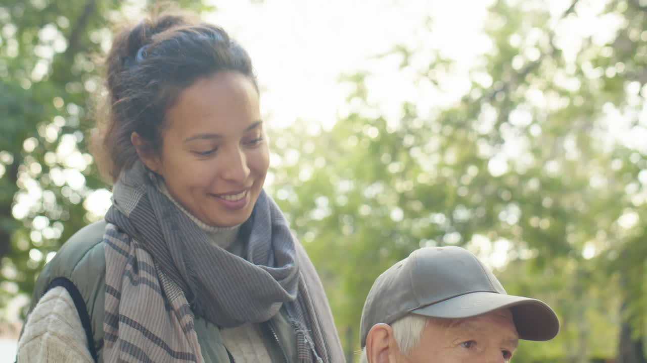 Senior Man in Wheelchair on Walk with Caregiver